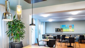 Un comedor moderno con una gran mesa de madera, sillas negras y lámparas colgantes.