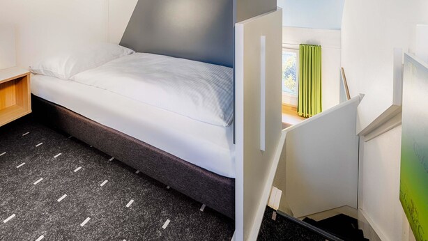 A modern hotel room with a bed, a desk, and a window with curtains. - B&B Hotel Köln-Frechen (Frechen)