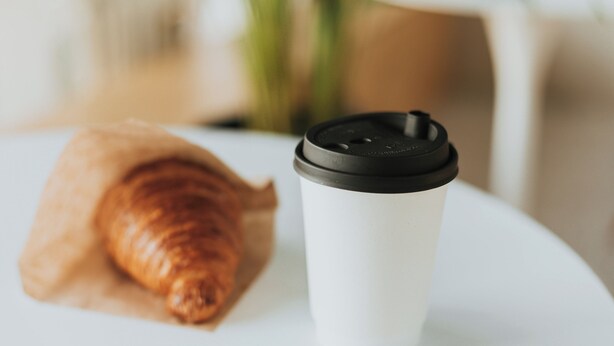 A croissant and a disposable coffee cup on a white plate. - Garner Hotel Cologne Engelbertz by IHG (Cologne)