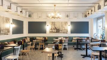 A restaurant with a central seating area, multiple tables and chairs, and a chandelier.