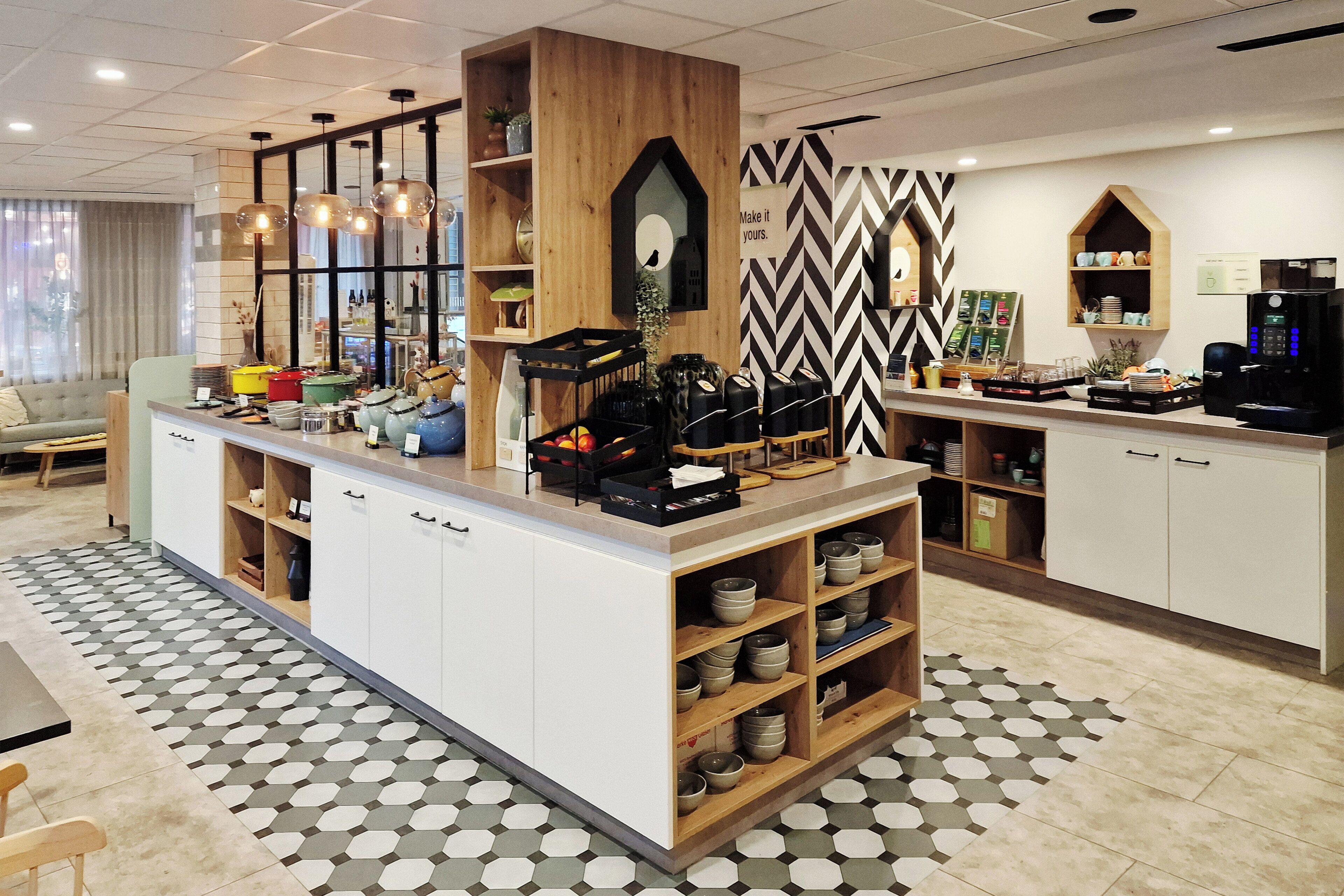 A modern kitchen area with a central island, wooden shelves, and a coffee machine.