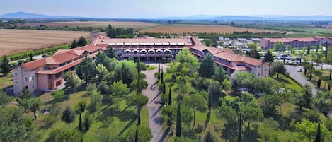 Un grand bâtiment à plusieurs étages doté d’une cour centrale entourée d’arbres, qui ressemble probablement à un hôtel ou à un complexe touristique.