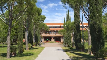 A building with a red-tiled roof, surrounded by trees and a pathway leading to the entrance.