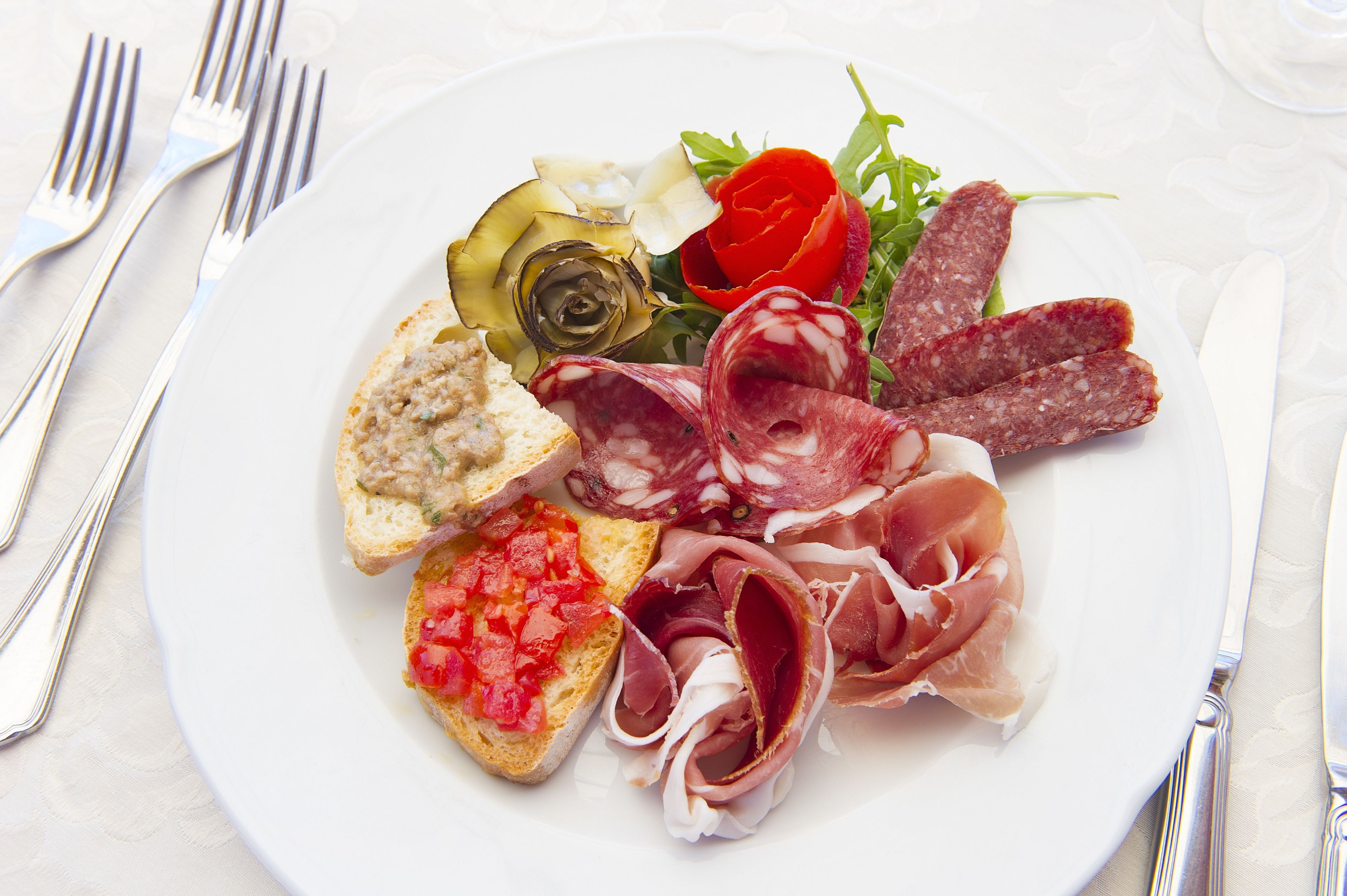 A plate of assorted meats, cheese, and vegetables on a white plate.