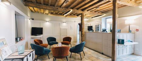 A room with a wooden ceiling, white walls, and a dining area with blue and brown chairs.