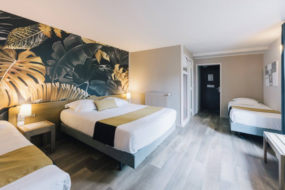A hotel room with a large bed, a smaller bed, a nightstand, a lamp, and a wall mural.