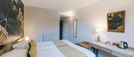A hotel room with a bed, bedside table, lamp, and artwork on the walls.