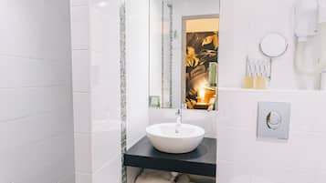 Un baño moderno con lavamanos blanco, encimera negra y un inodoro.
