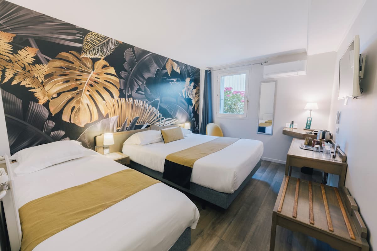 A hotel room with two beds, a wooden nightstand, a desk, and a large window with curtains.
