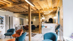 A modern interior with exposed wooden beams, a reception desk, and several seating areas with chairs. - Logis Hôtel la Grassinais Saint-Malo (Saint-Malo)