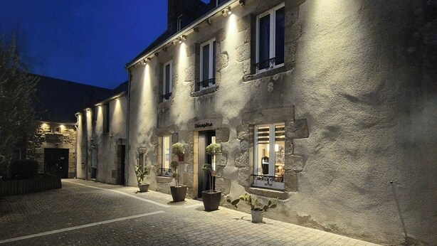 A stone building with a reception area, potted plants, and a cobblestone courtyard. - Logis Hôtel la Grassinais Saint-Malo (Saint-Malo)