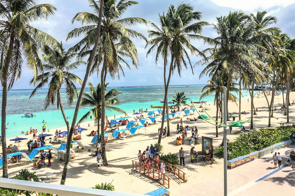 Une plage bordée de palmiers, une étendue de sable et une mer d’un bleu limpide.