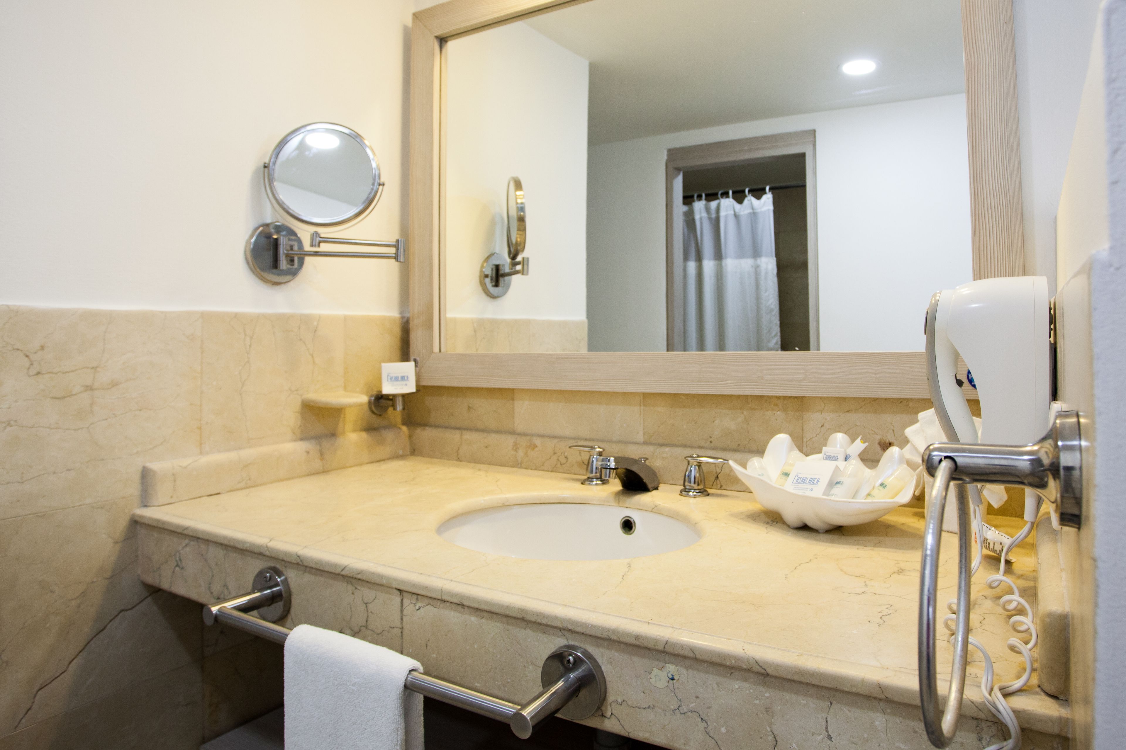 Une salle de bain équipée d’un lavabo, d’un miroir, d’un porte-serviettes et d’un s èche-cheveux.