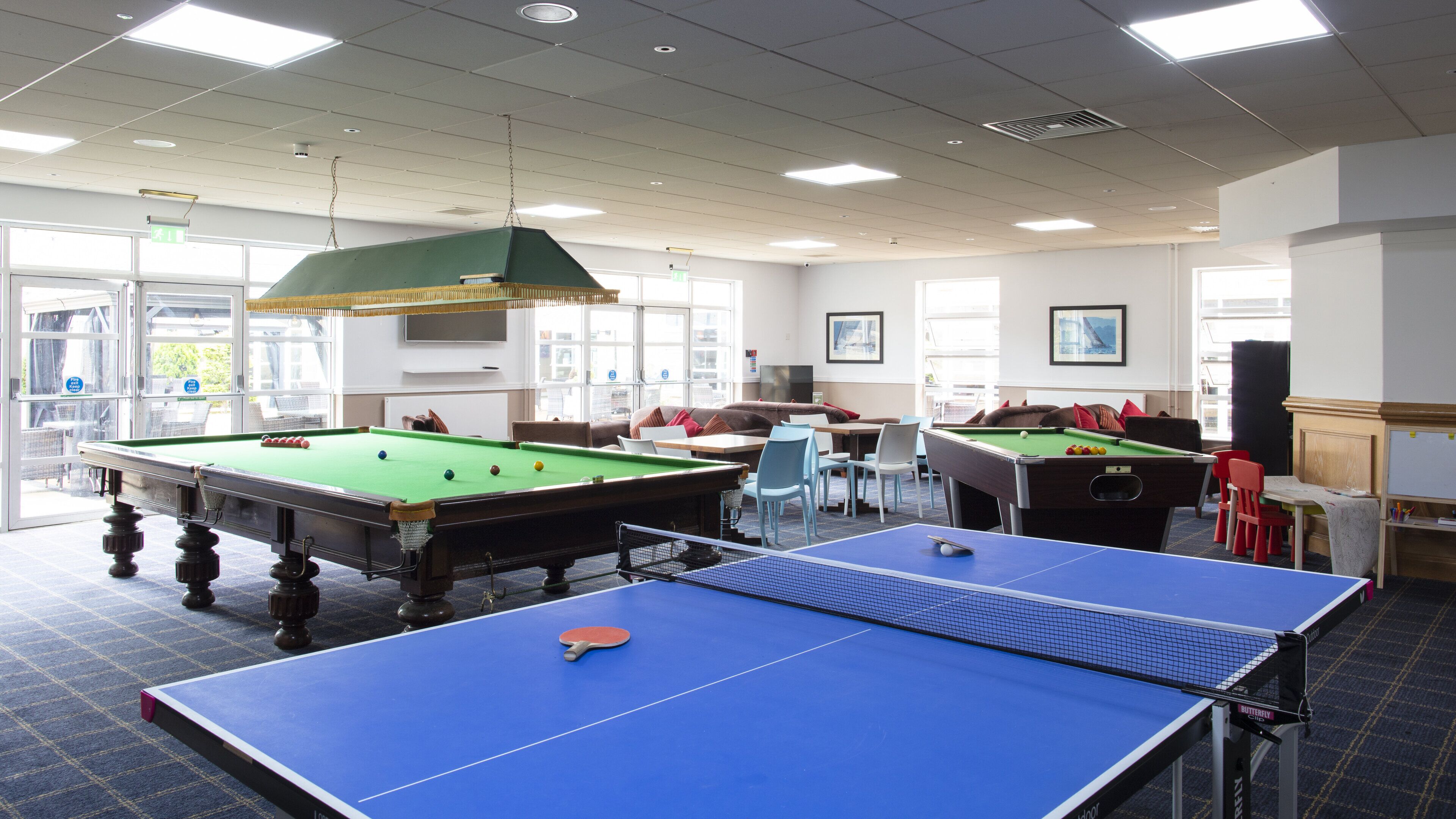 A room with pool tables, a ping pong table, and a sofa.