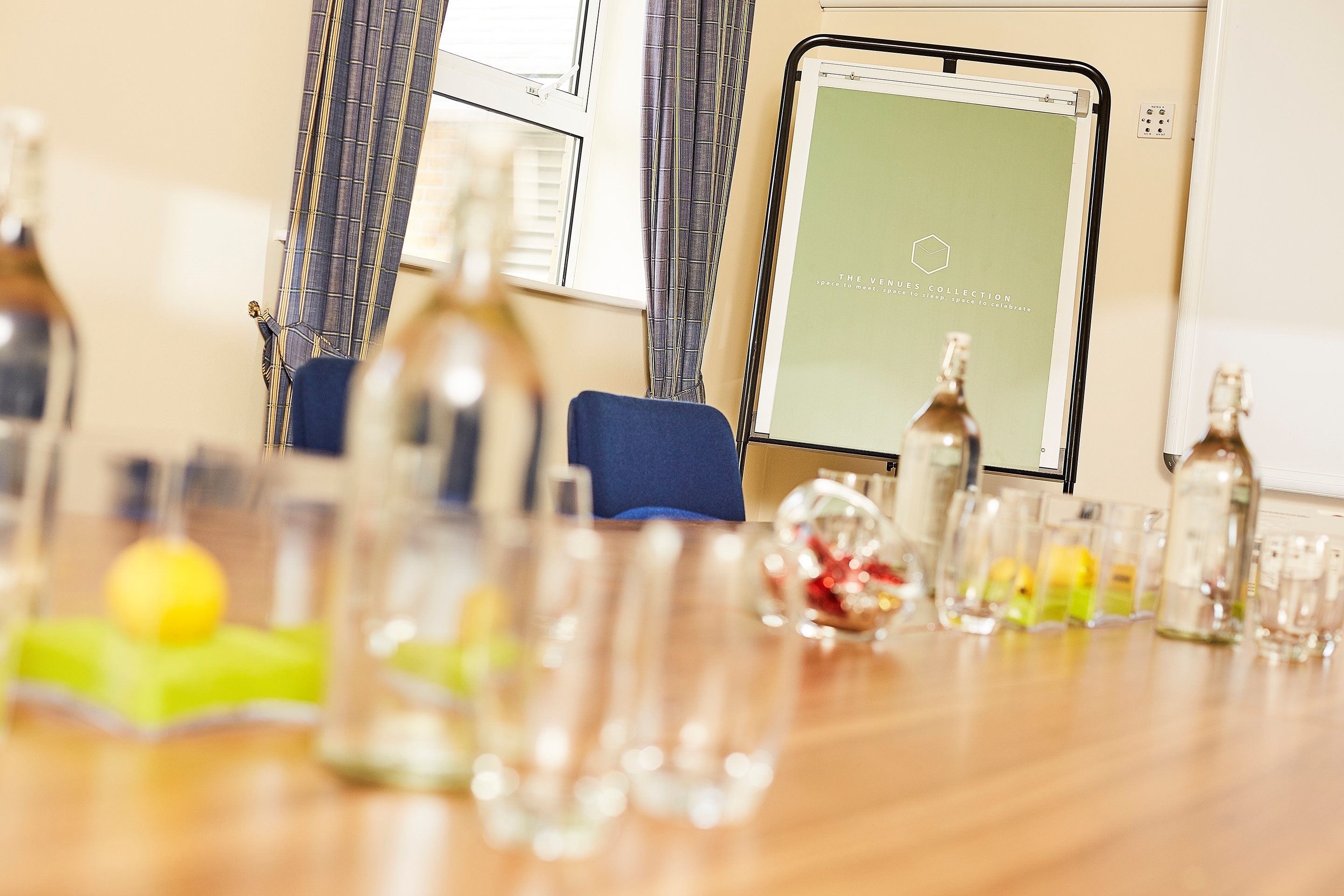 A room with a wooden table, a laptop, and various bottles and glasses.