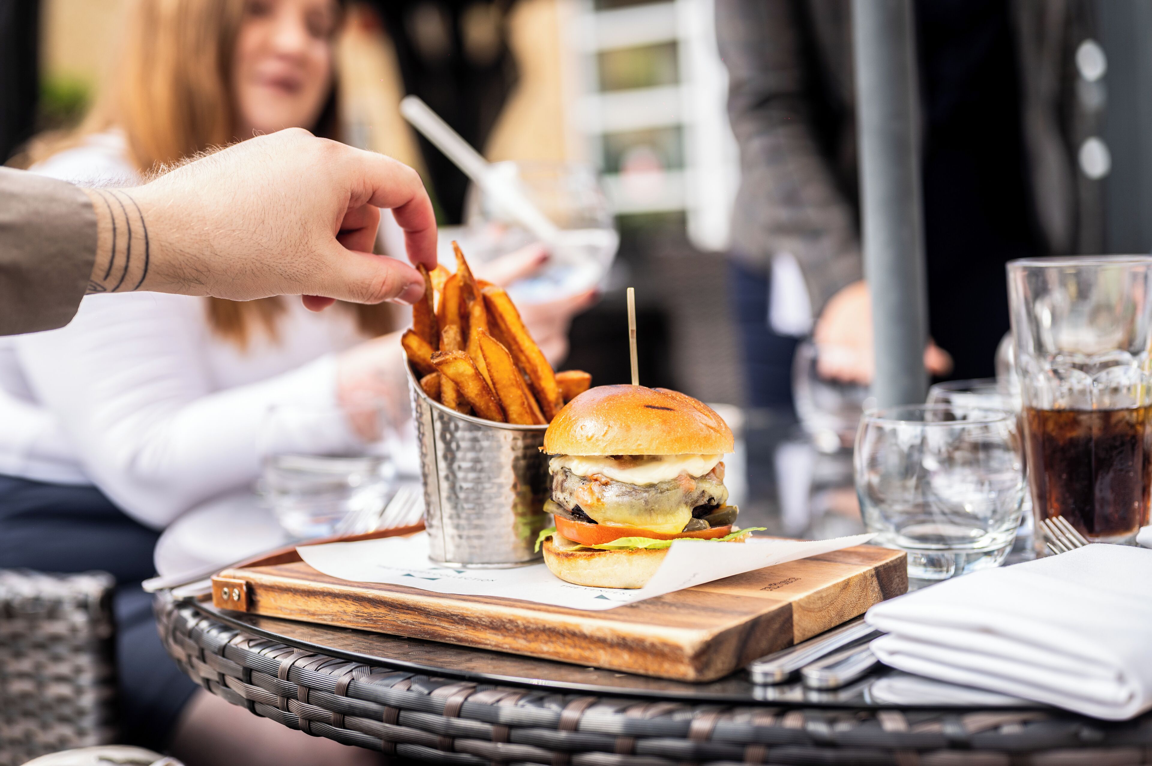 A meal setting with a burger, fries, and drinks on a table.