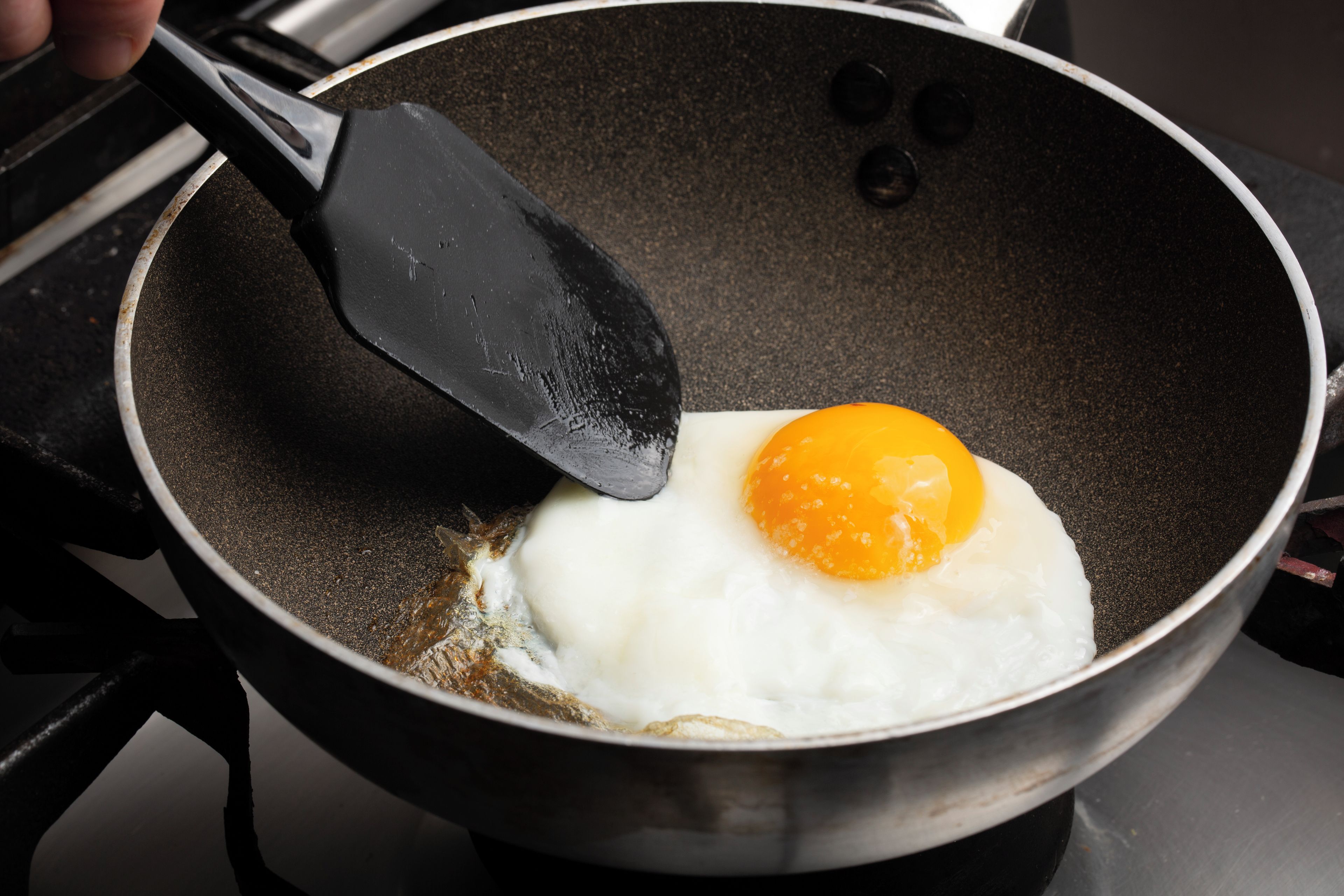A frying pan with a single egg being cooked on a stove.