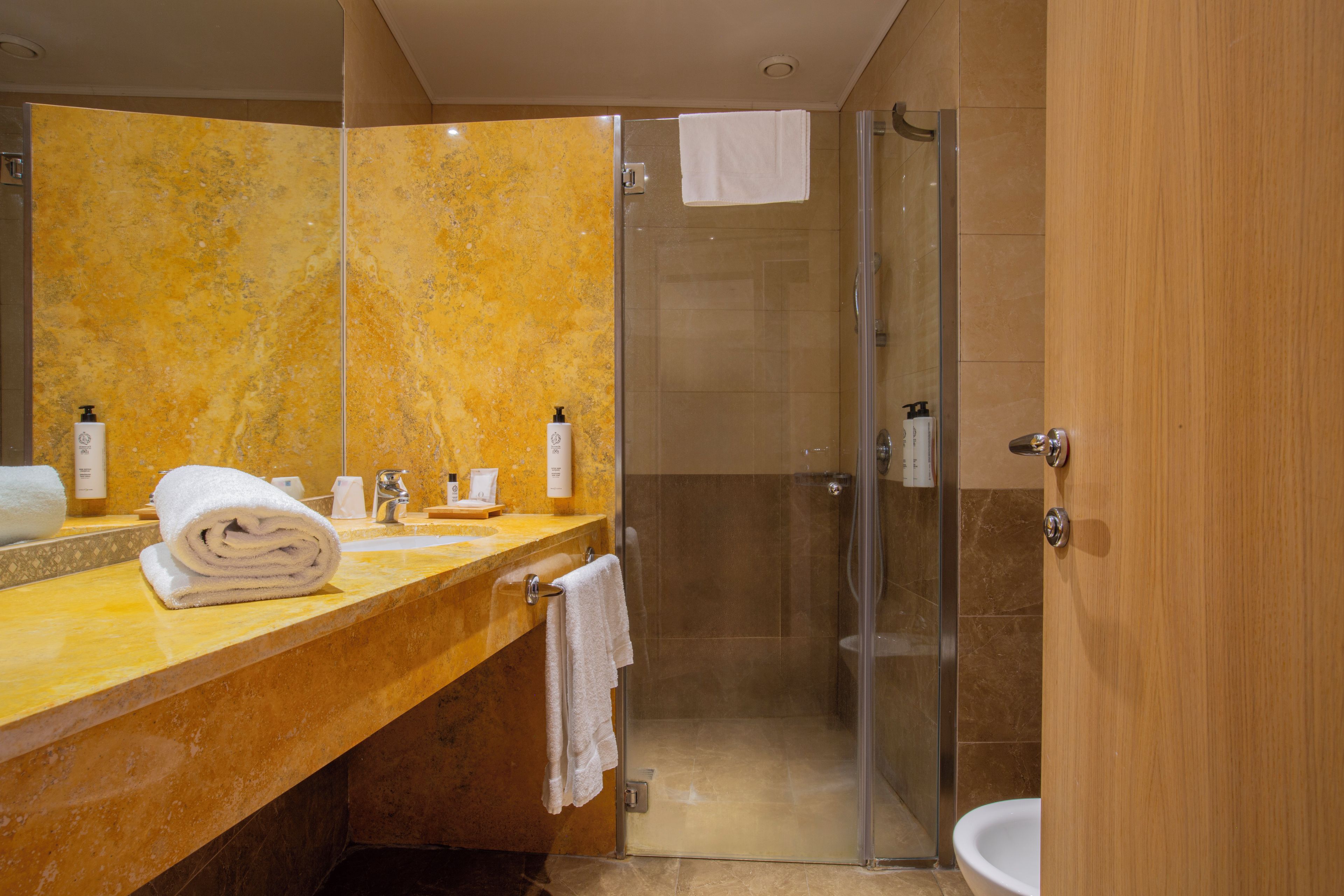 Ein modernes Badezimmer mit Marmor-Waschtisch, einer Glasdusche und einem weißen Waschbecken.