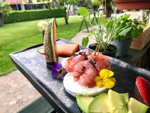 Ein Tablett mit verschiedenen Speisen, darunter Garnelen, Avocado und eine Blume.