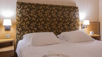 Habitación de hotel con una cama grande, dos lámparas de noche, una mesita de noche y una lámpara de pared.