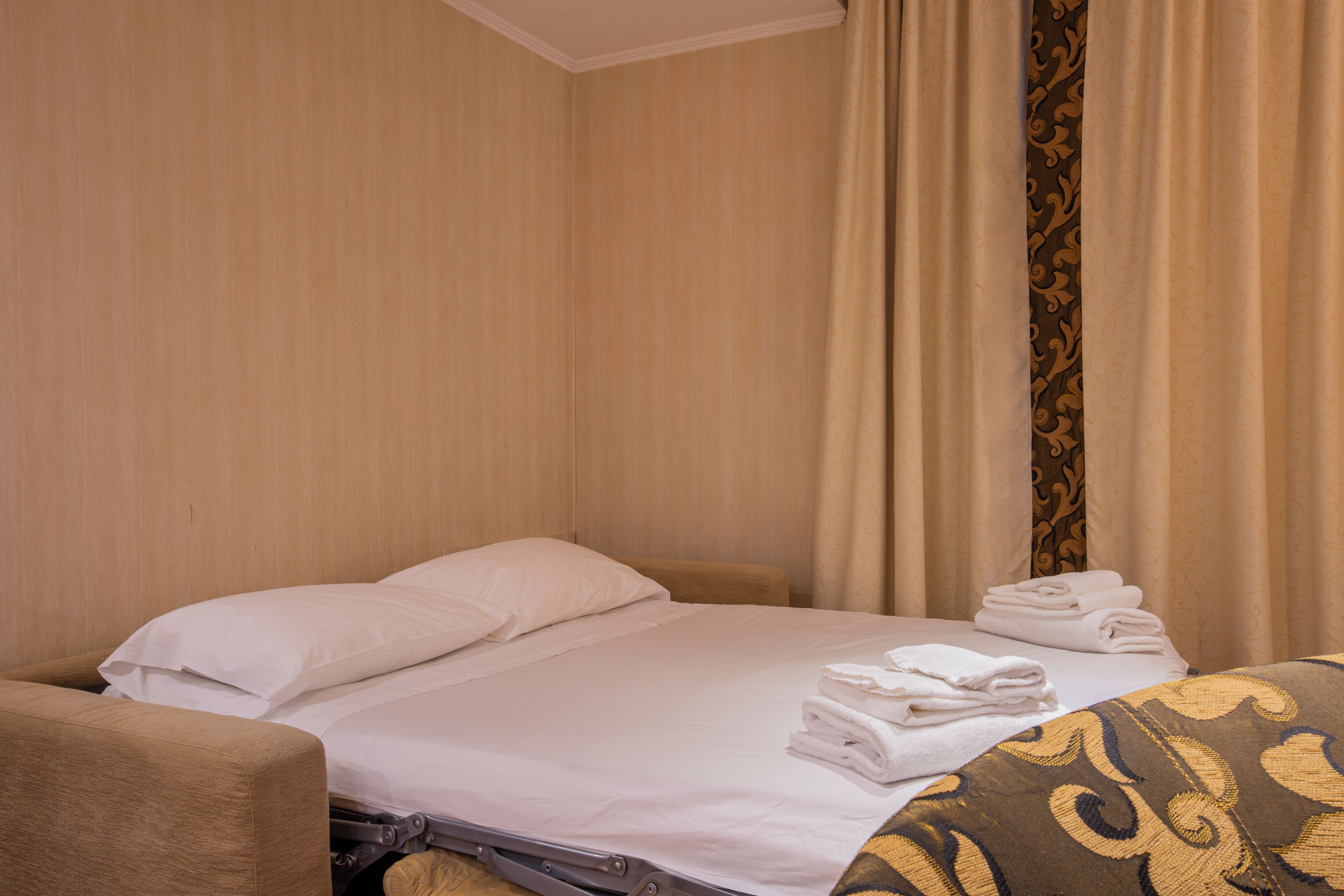 A hotel room with a bed, pillows, a chair, and a set of towels.