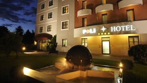 Ett hotell med en skylt som visar texten ”POL HOTEL” och en fontän eller något liknande i förgrunden.