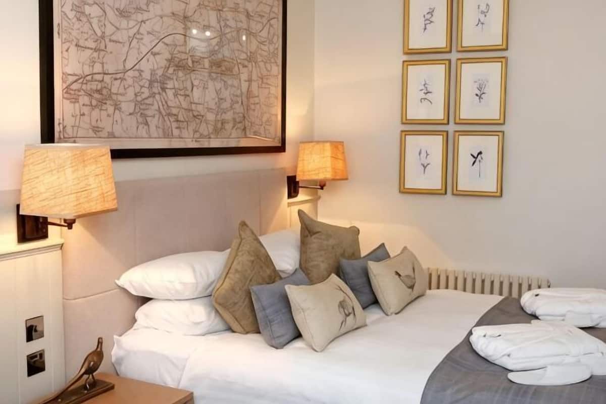 A neatly made bed with pillows, a map on the wall, and framed pictures.
