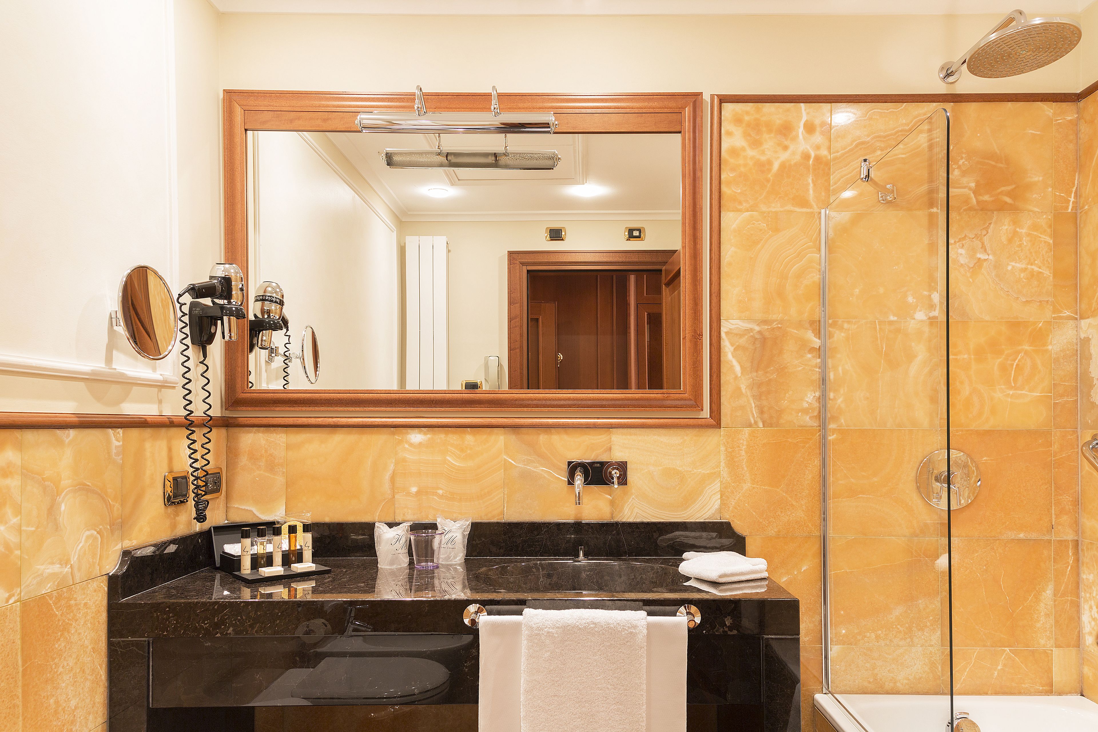 Un baño con tocador de mármol, un espejo grande, cabina de ducha y un perchero para toallas.