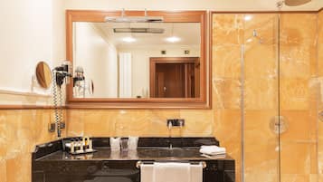 Un baño con tocador de mármol, un espejo grande, cabina de ducha y un perchero para toallas.