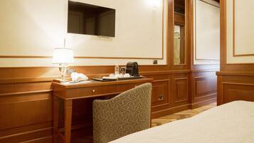 Una habitación de hotel con una cama, un escritorio con lámpara, un teléfono y una cafetera.