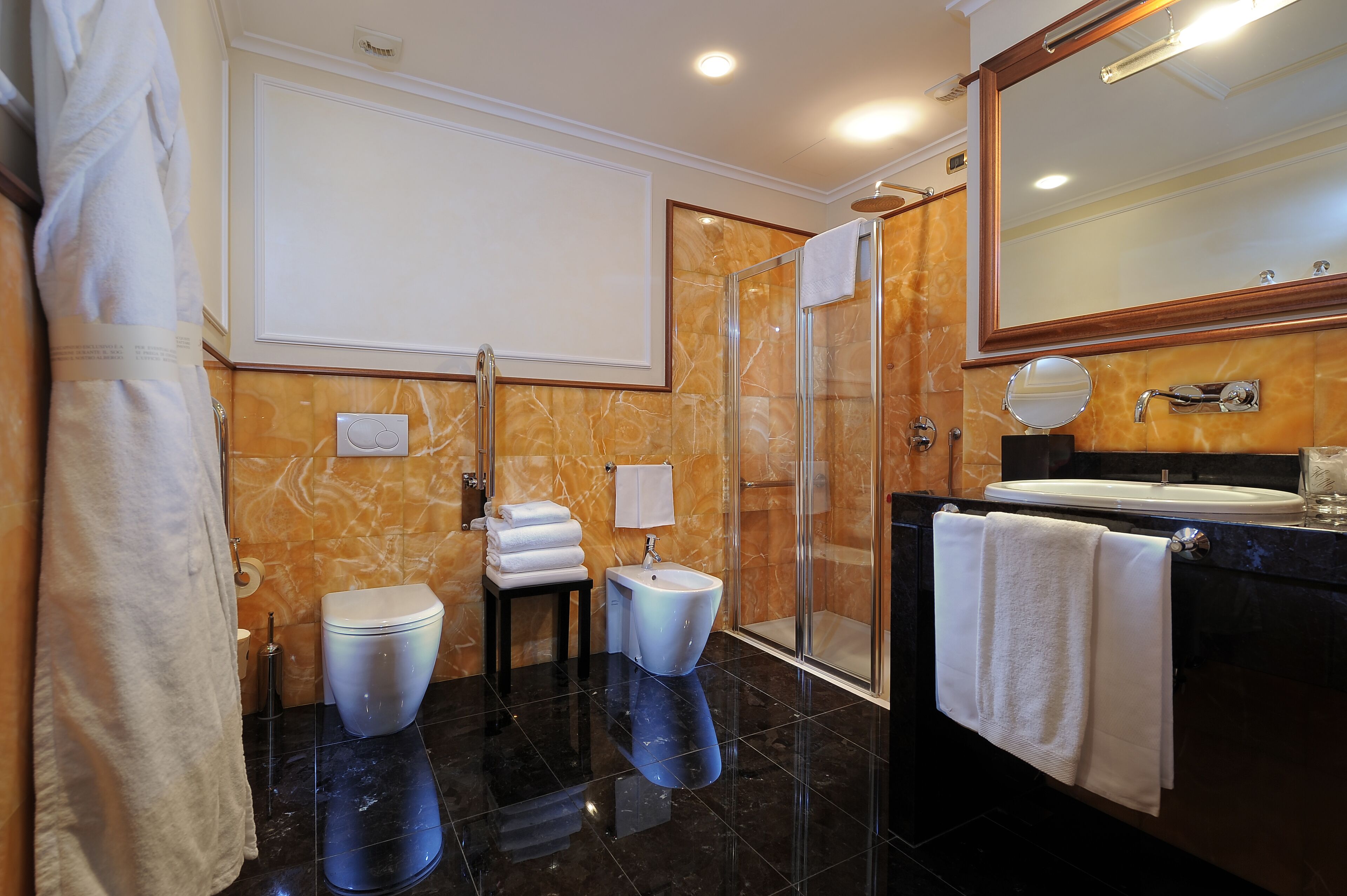 Une salle de bain moderne dotée d’une douche à parois de verre, de toilettes, d’un bidet et d’un meuble-lavabo avec un miroir.