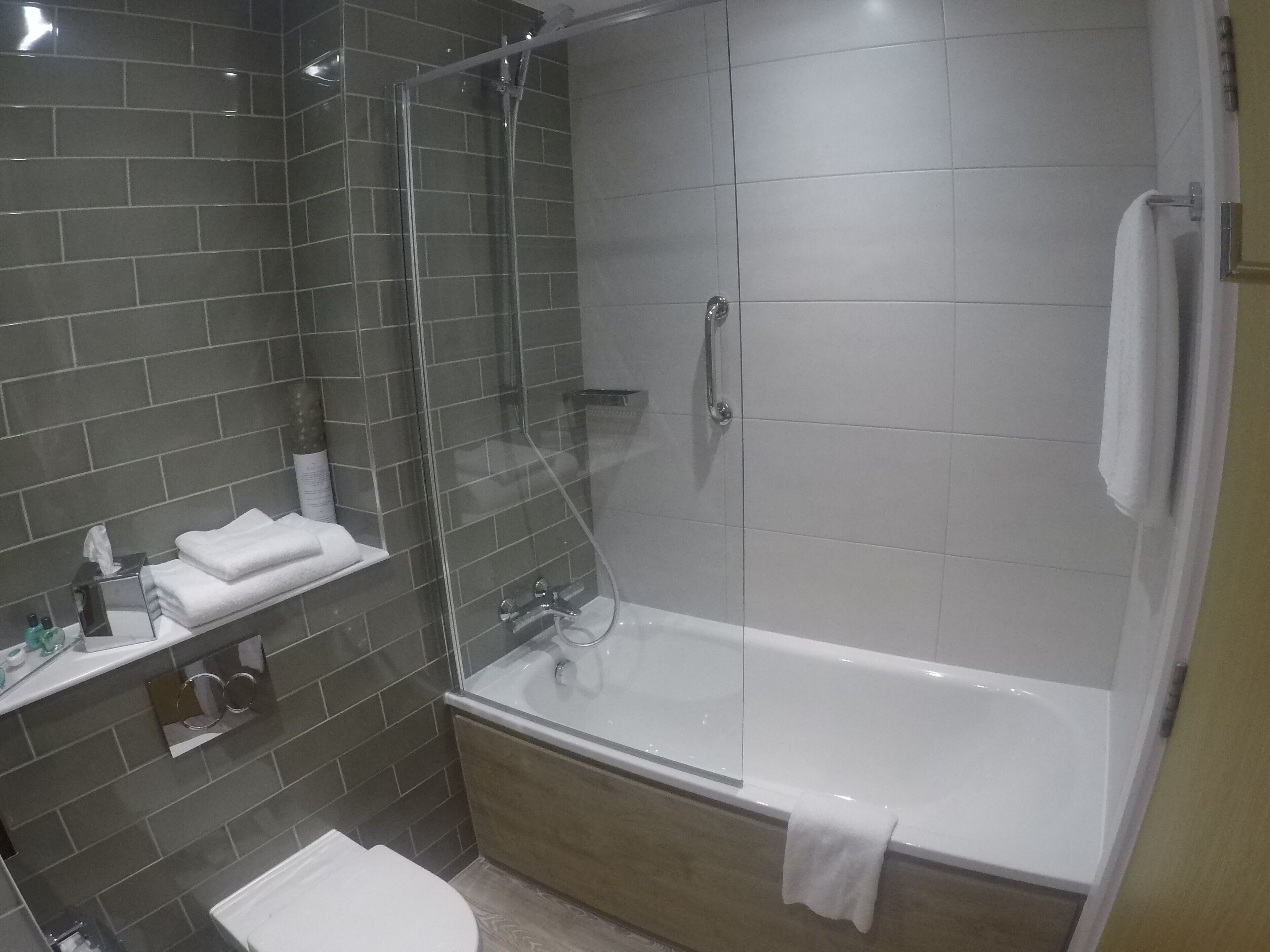 Un baño moderno con ducha de vidrio, una bañera blanca y un lavabo con espejo.
