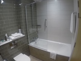 Un baño moderno con ducha de vidrio, una bañera blanca y un lavabo con espejo.