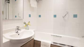 Un baño moderno con un lavamanos blanco, un box de ducha de vidrio y una bañera.