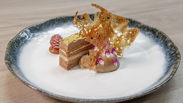 A dessert plate with a layered cake, a spherical dessert, and decorative elements on a ceramic plate.