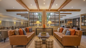 A spacious living area with leather sofas, a central coffee table, and a large window providing natural light.