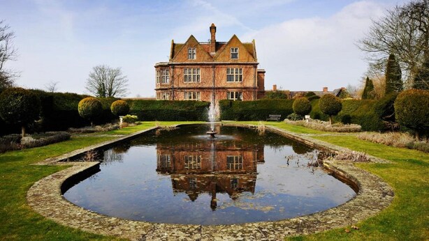A large brick building with a symmetrical garden and a central fountain.