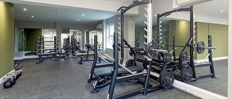 Un gimnasio con diversos equipos de ejercicio, como cintas de correr, máquinas de pesas y pesas libres.