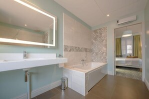 A modern bathroom with a large mirror, two sinks, a bathtub, and a shower. - Arcantis Hotel Heritage (Cognac)