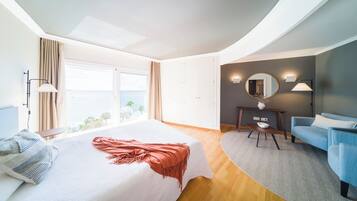 Ein Hotelzimmer mit Bett, einer Couch, einem Schreibtisch und Meerblick.