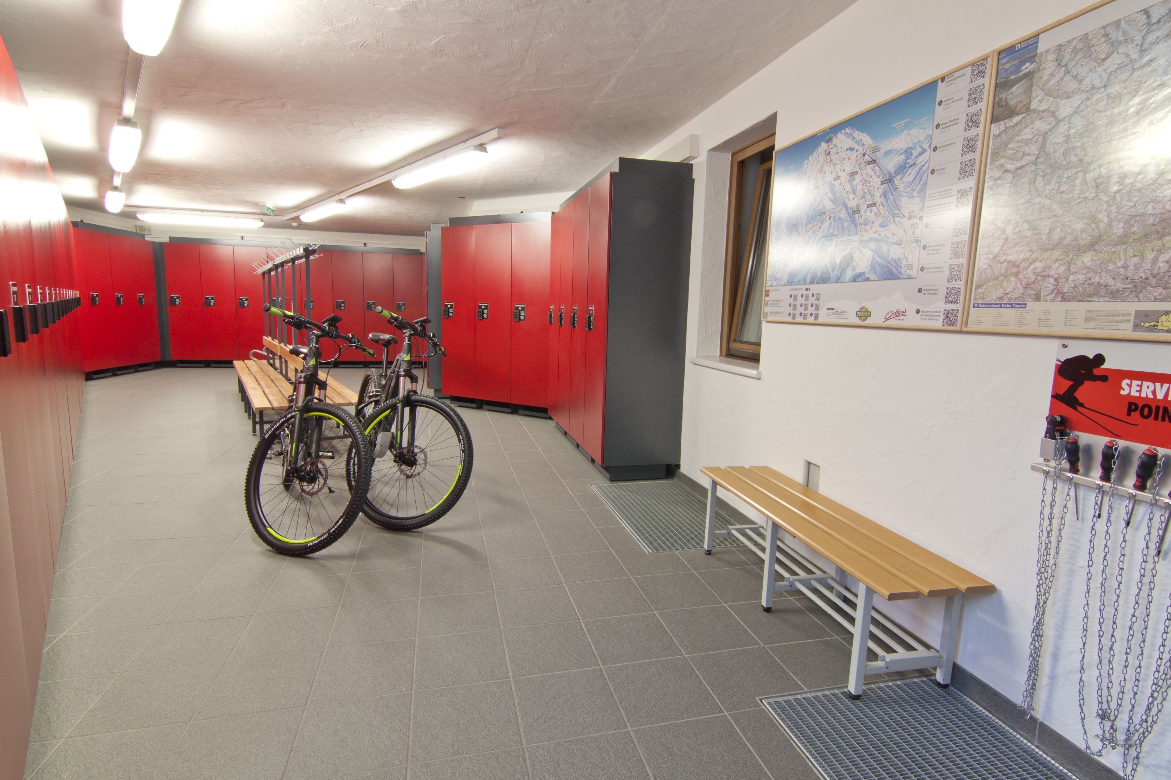 A locker room with red lockers, bicycles, and benches.