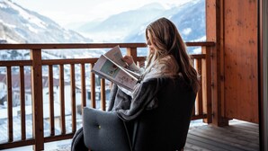 A person reading a book on a wooden balcony with a mountain view. - Naturhotel Outside (Matrei in Osttirol)