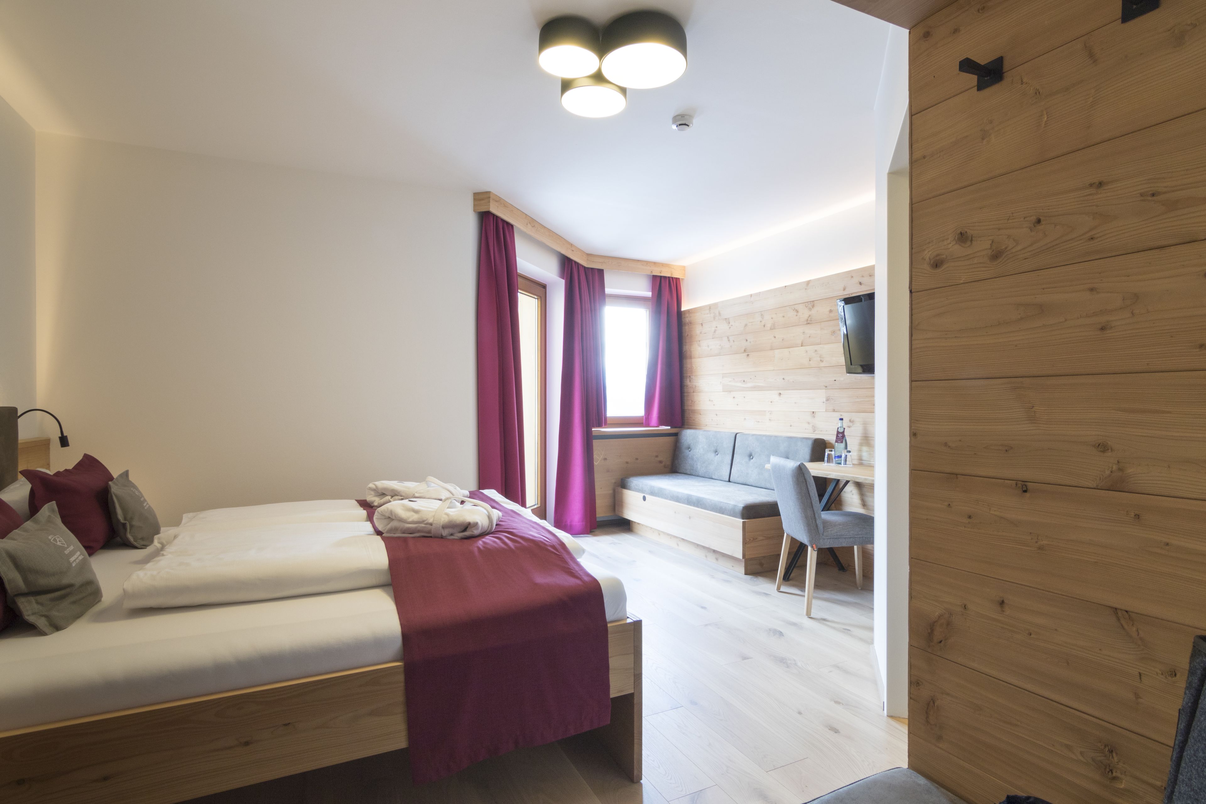 A modern bedroom with a bed, a desk, and a seating area.