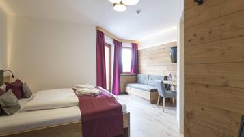 A modern bedroom with a bed, a desk, and a seating area.