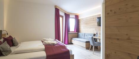 A modern bedroom with a bed, a desk, and a seating area.