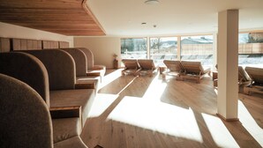 A modern interior with wooden flooring, a curved ceiling, and seating areas with a view of the outdoors. - Naturhotel Outside (Matrei in Osttirol)