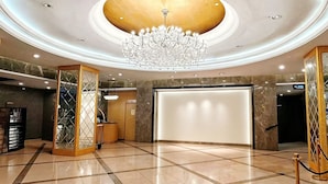 Eine großzügige Lobby mit einem imposanten Kronleuchter, einer Rezeption und einem modernen Design.
