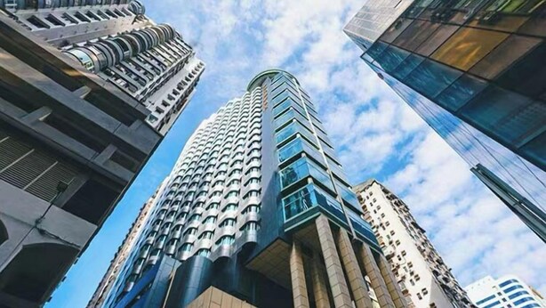 Ein hoch aufragendes Gebäude mit modernem Design, das eine markante Glasfassade und mehrere Balkone aufweist.