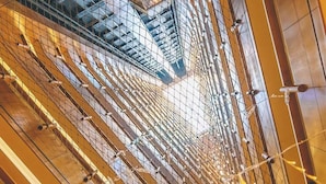 Ein modernes Interieur mit einem geometrischen Deckenmuster, Metallgeländern und sternförmigen Leuchten.