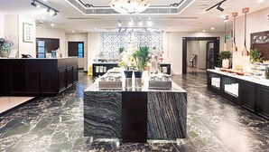 Eine Hotelhalle mit einer Rezeption, einer zentralen Pflanzentheke und einem gemusterten Boden.